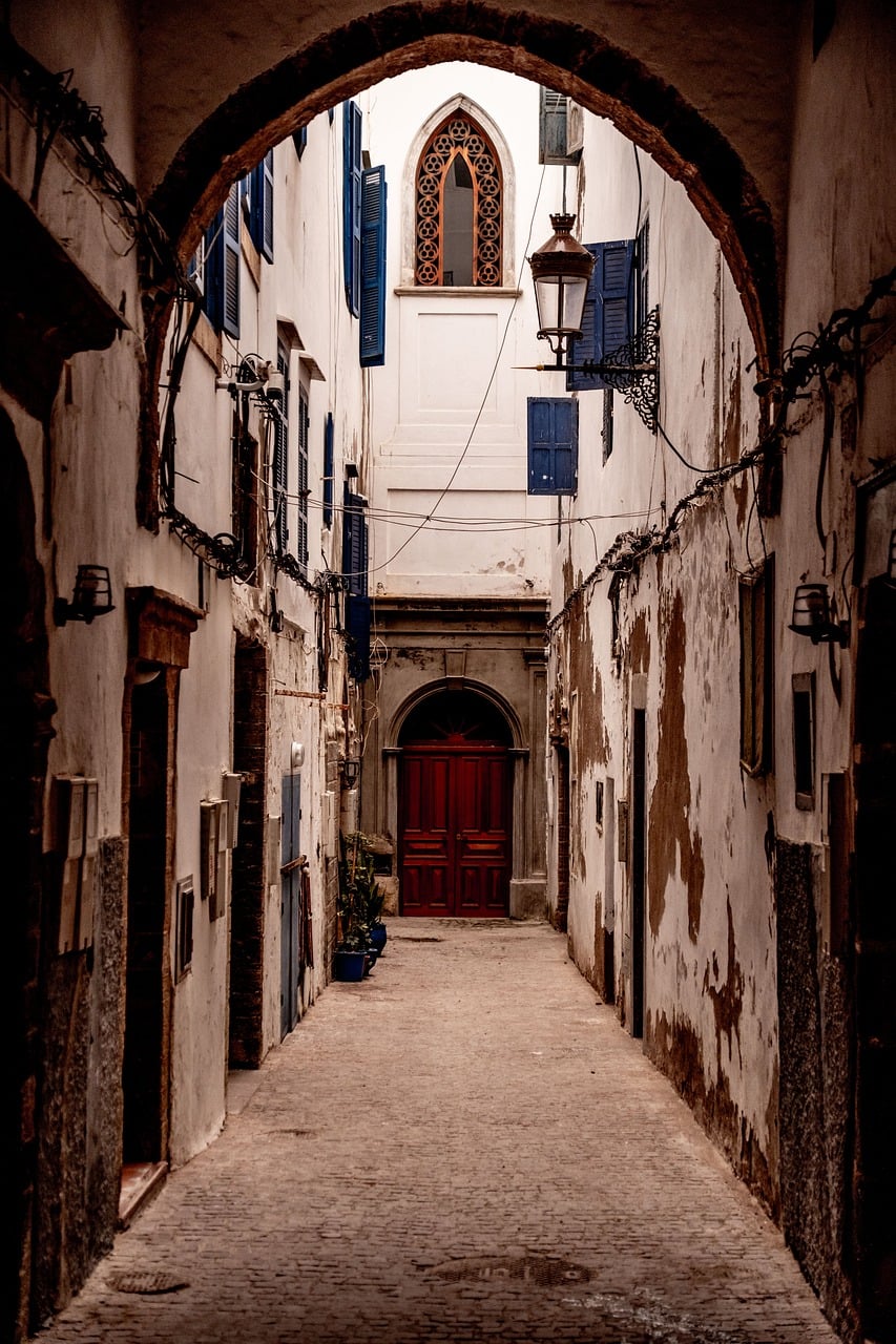 morocco, essaouira, architecture, old alley, wooden door, blue shutters, stone path, street lamp, window, grand arch, city alley, historic building, romantic view, historical quarter, narrow architecture, street charm, eye for architecture, rocky urban terrain, completely deserted