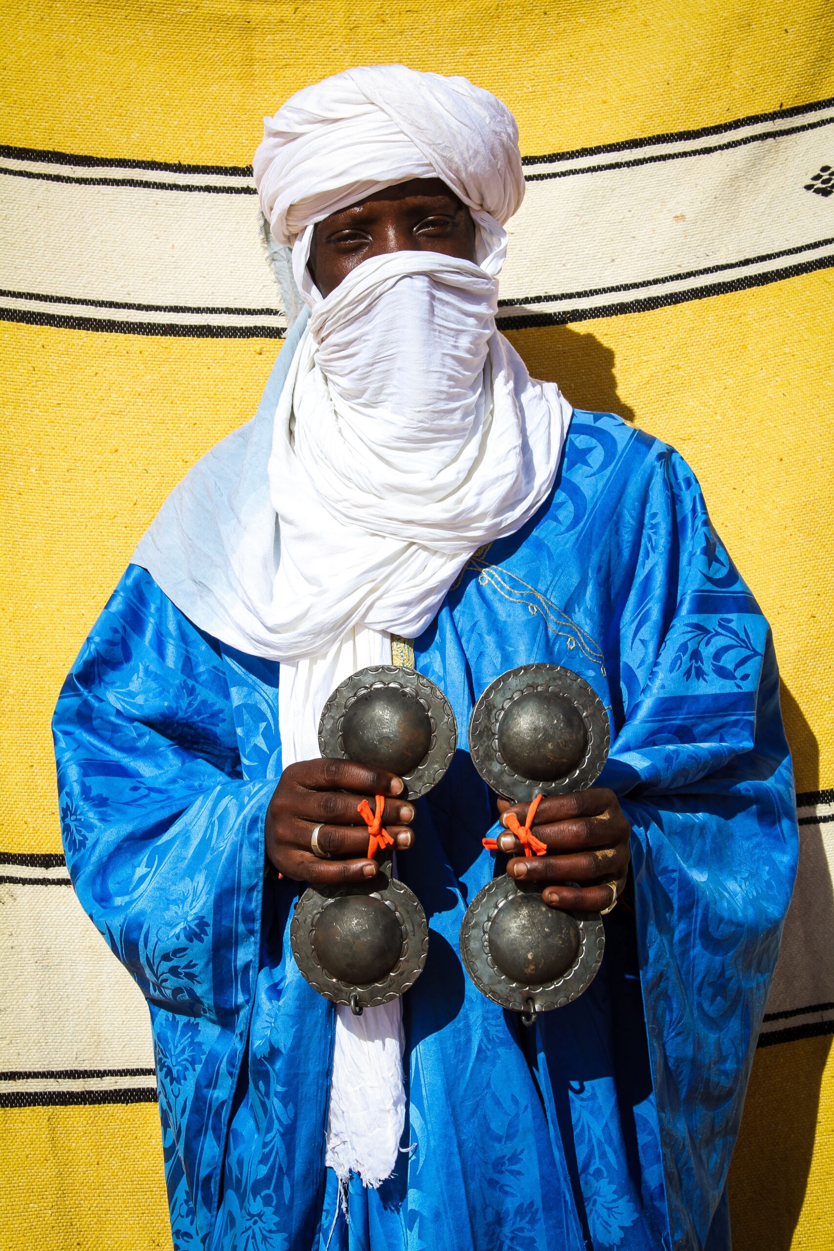 A Moroccan musician in traditional attire holding krakeb, showcasing Gnawa culture.