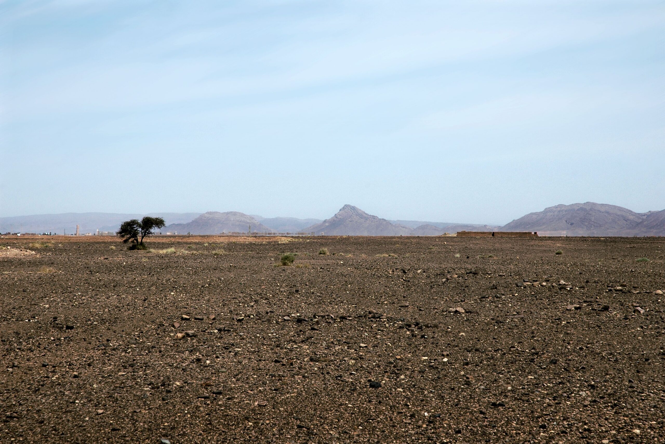 Expansive desert view with mountains in M'Hamid El Ghizlane, Morocco under a clear sky.