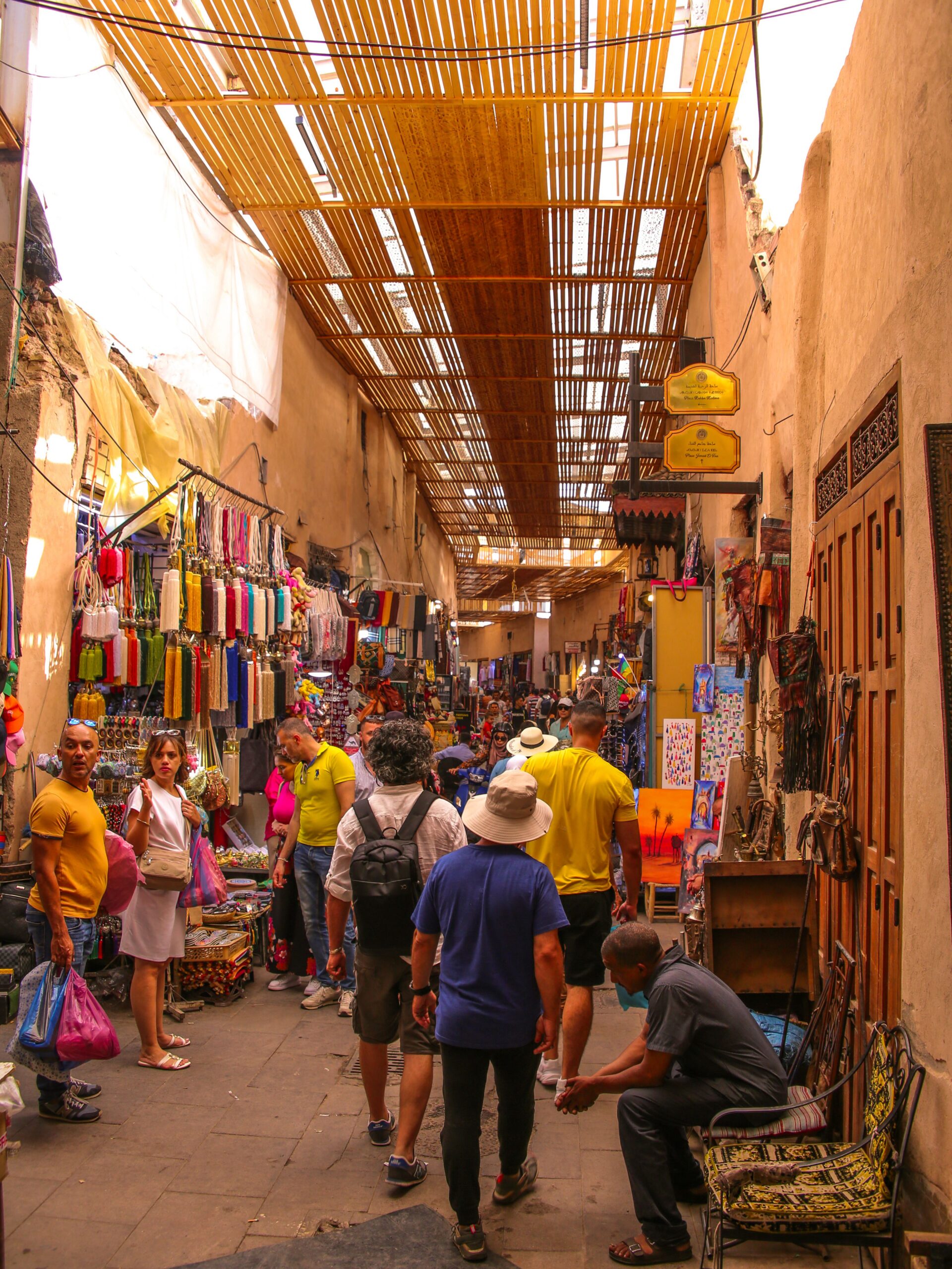 Busy street scene in Marrakech medina featuring colorful shops and local visitors. Experience Moroccan culture.