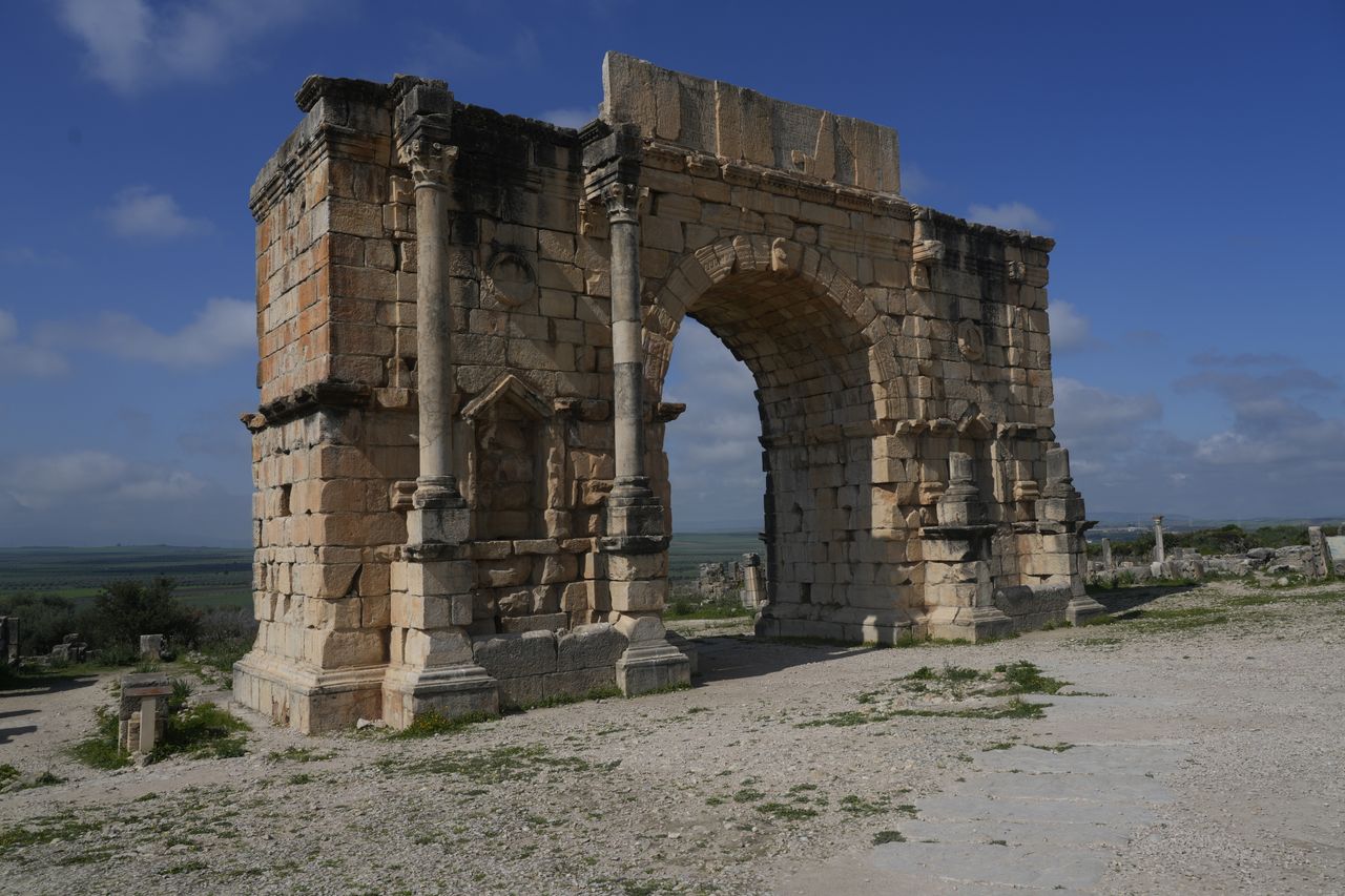 Captured at the ancient site of Volubilis, this arch stands under a clear blue sky, showcasing Roman architectural prowess.
