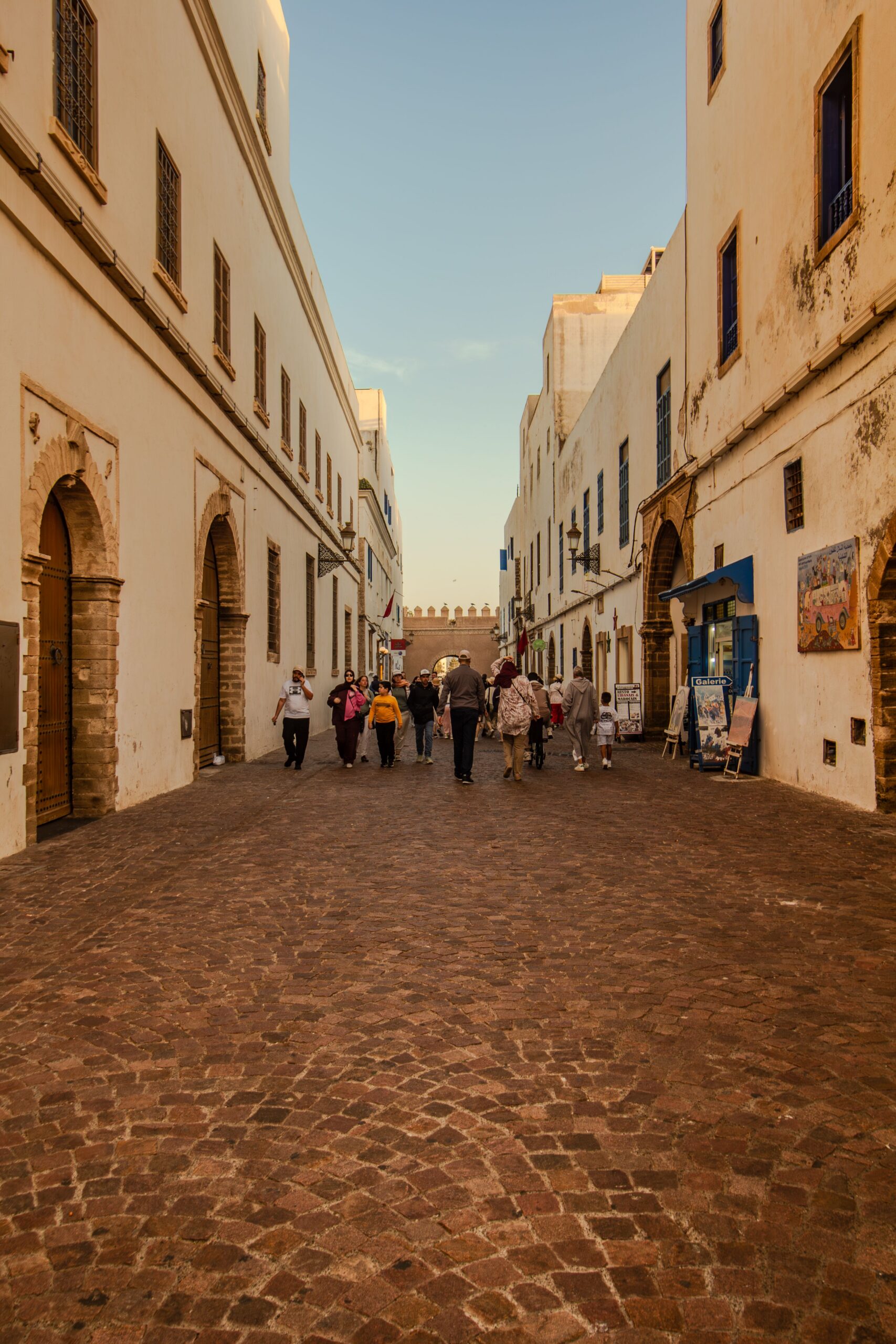 Charming street scene in Essaouira, Morocco showcasing local architecture and tourists.