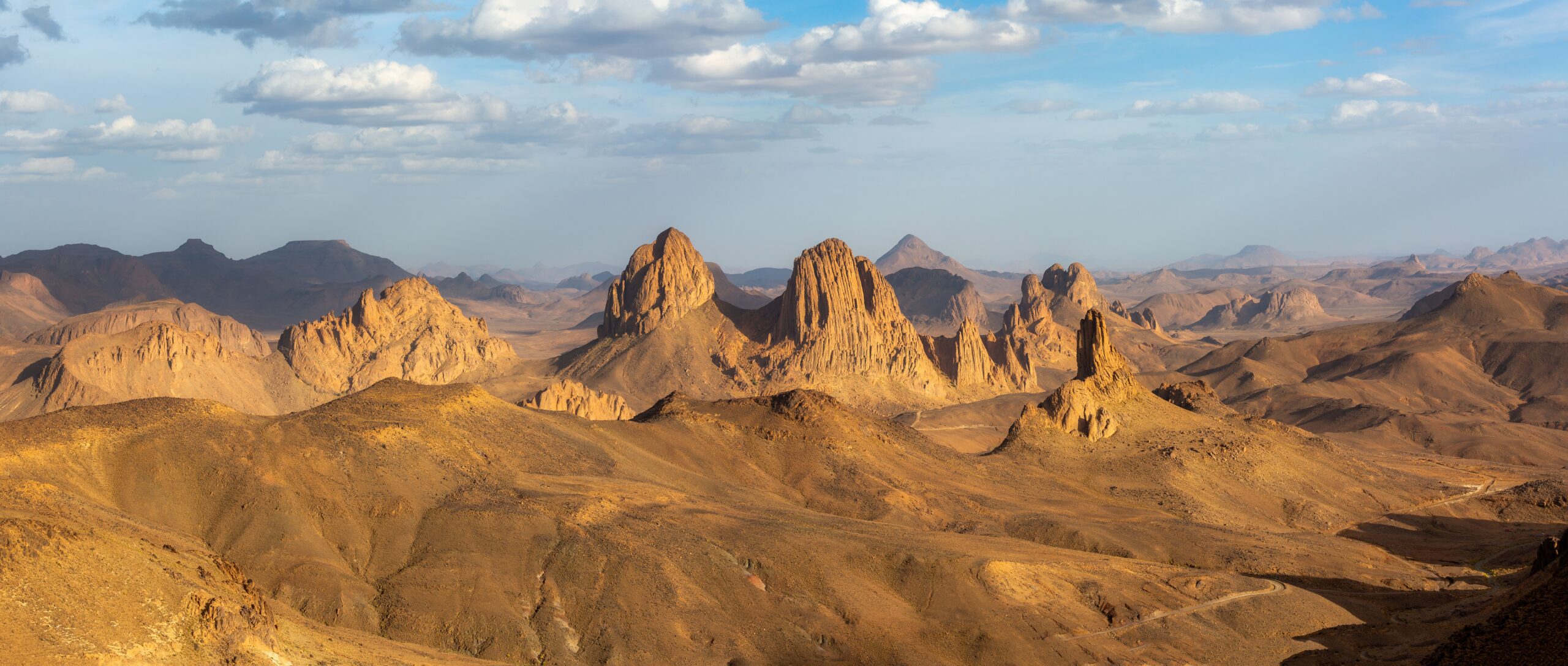 Panoramic view of rocky formations in the Sahara desert under a clear blue sky.