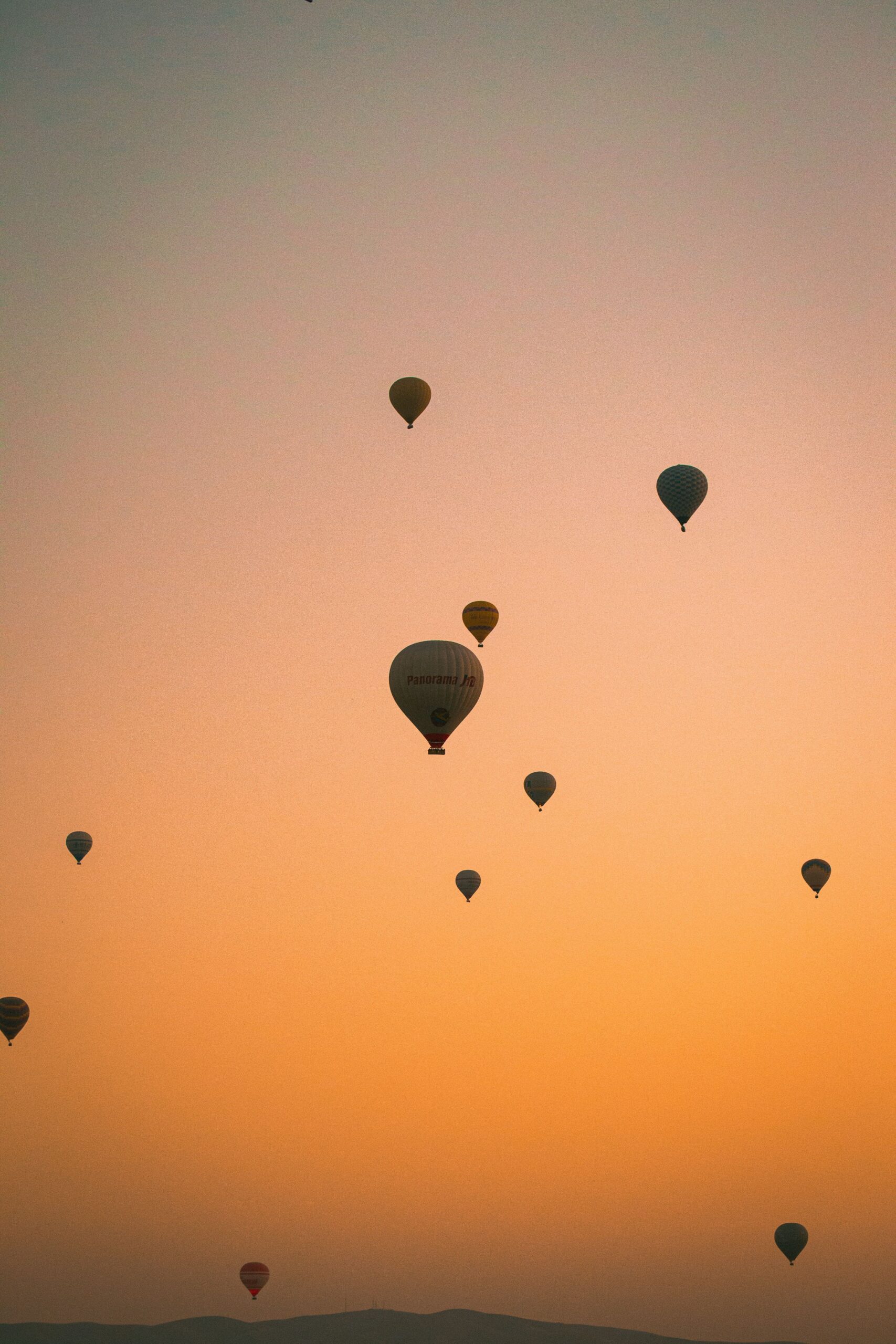 Hot air balloons rise against a stunning Cappadocia sunset, capturing the magic of Türkiye's skyline.